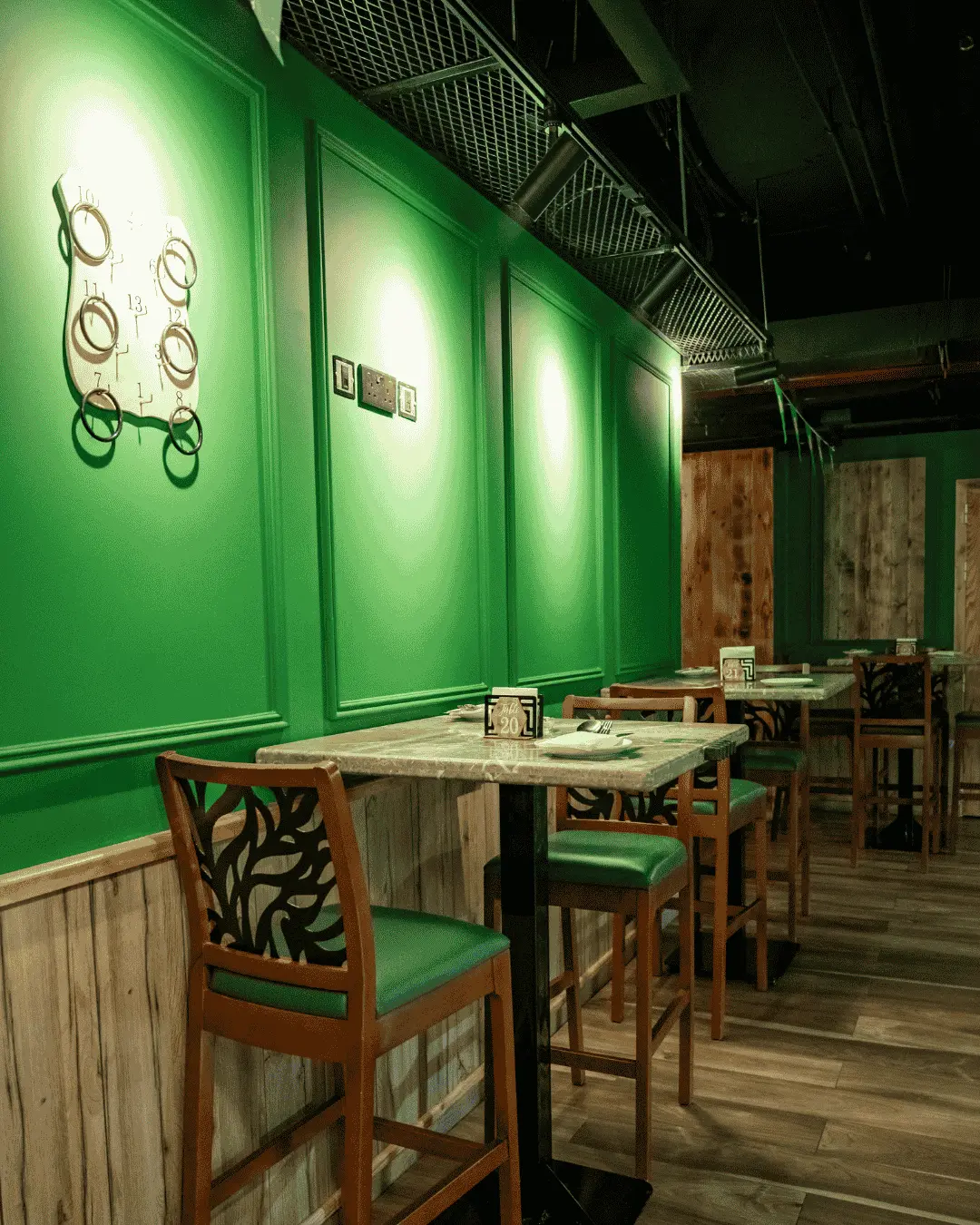 High tables and green-seated chairs along a green-panelled wall at Irish Inn
