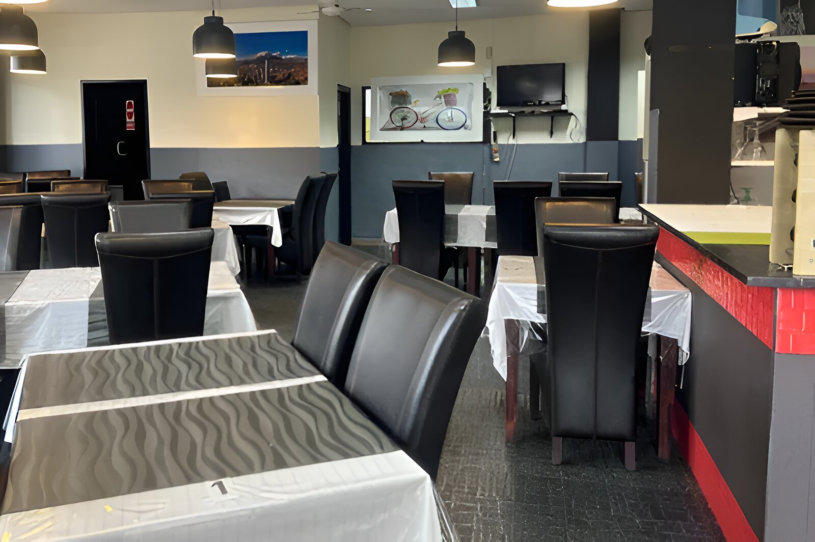 The dining room at Mumtaz Curry House, with high-backed black chairs and a red bar counter